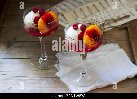 Gelato di pesche e salsa di lamponi dessert dedicata alla Australian cantante lirica Melba. Stile rustico. Foto Stock