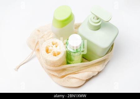 Diversi contenitori per shampoo, balsamo, tonico, sapone liquido in eco bag. Panno di lavaggio in loofah o luffa, spugna vegetale, alternativa alla plastica Foto Stock