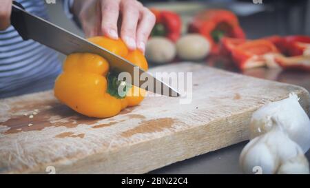 affettare i peperoni gialli, cuocere le verdure, preparare i peperoni gialli e rossi. Ingredienti vegetali per una cena o un pranzo sani. Pep. Condimento Foto Stock