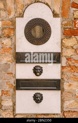 Primi piani di facciate di edifici a Venezia. Un vecchio citofono vintage e una casella postale su una parete di pietra. Sulla porta dove si sono collocate queste vecchie campane arrugginite. Foto Stock