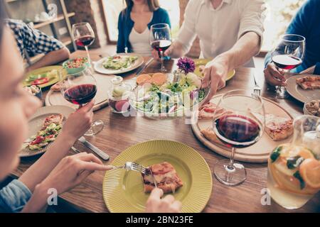 Primo piano con una foto ritagliata di un tavolo di legno ben servito con piatti gustosi e bicchieri di vino rosso. Il ragazzo sta passando insalata fresca all'altro lato di Foto Stock