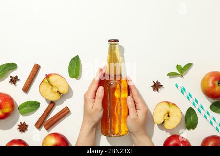 Le mani femminili tengono il flacone di sidro su sfondo bianco. Composizione con sidro Foto Stock