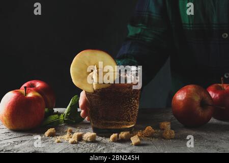 Donna tenere il bicchiere di sidro. Composizione con sidro su tavolo grigio Foto Stock