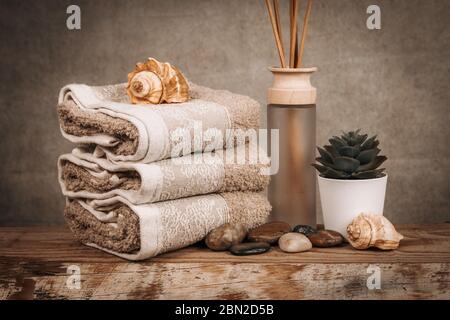 Essenziale per il centro benessere, bastoncini di aroma, pietre, asciugamani, guscio di mare su sfondo rustico in legno Foto Stock