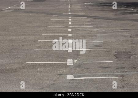 Segni bianchi vecchi, sporchi e sbiaditi in un parcheggio vuoto Foto Stock