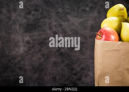 mele e pere in un sacchetto di carta artigianale su sfondo scuro Foto Stock