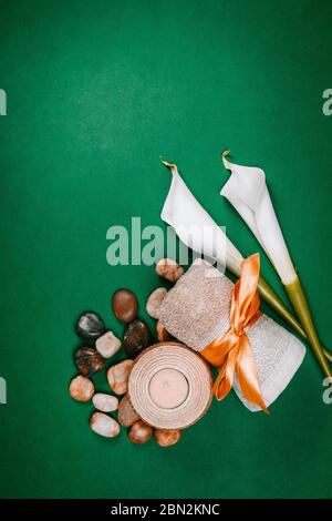 Prodotti essenziali per il benessere, bastoncini, pietre, asciugamani, conchiglia di mare su sfondo verde Foto Stock