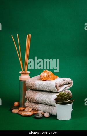 Prodotti essenziali per il benessere, bastoncini, pietre, asciugamani, conchiglia di mare su sfondo verde Foto Stock