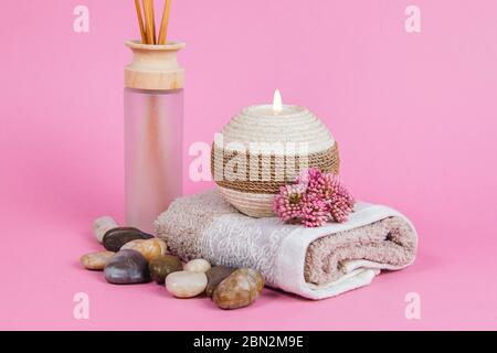 Prodotti essenziali per il benessere, bastoncini, pietre, asciugamani, conchiglia di mare su sfondo rosa Foto Stock