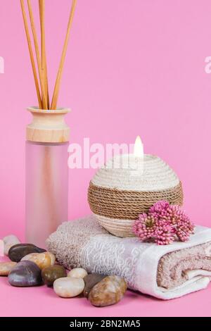 Prodotti essenziali per il benessere, bastoncini, pietre, asciugamani, conchiglia di mare su sfondo rosa Foto Stock