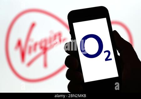 logo o2 della rete di telefonia mobile su un telefono cellulare con il logo Virgin Media dietro. (Solo per uso editoriale) Foto Stock