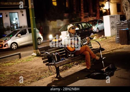 TEL AVIV, ISRAELE - 12 ottobre 2013: Musicista e cantante di strada cieco con chitarra seduta su un banco su Rothschild Boulevard di notte Foto Stock