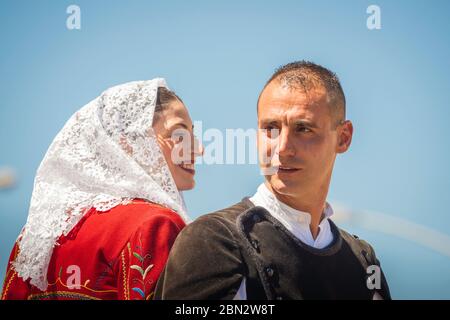 Ritratto di una giovane coppia cavalcare insieme indossando il costume tradizionale in parata della Cavalcata Sarda festival di Sassari, Sardegna Foto Stock