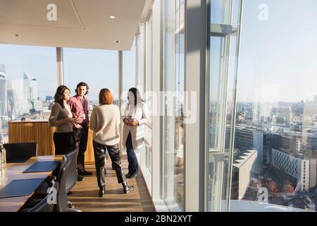 Gli uomini d'affari parlano alla luminosa finestra dell'ufficio Foto Stock