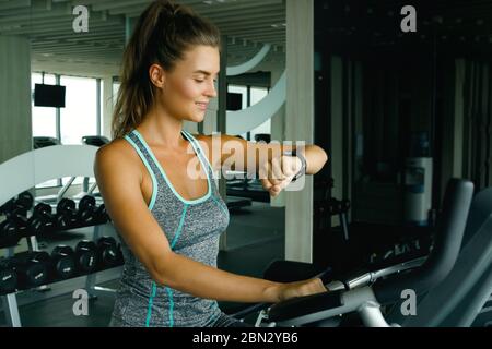 Donna sta usando l'orologio intelligente durante il suo workout nella palestra Foto Stock
