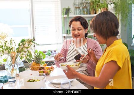 Donne amici mangiare insalata in cucina Foto Stock