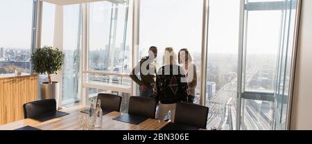 Gli uomini d'affari parlano alla luminosa finestra dell'ufficio Foto Stock