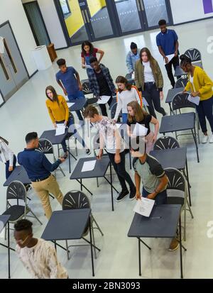 Vista dall'alto degli studenti delle scuole superiori che terminano l'esame alle scrivanie Foto Stock