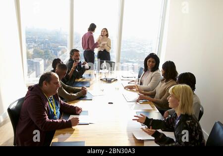 Uomini d'affari che parlano in una soleggiata sala conferenze Foto Stock