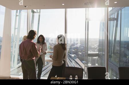 Gli uomini d'affari parlano alla luminosa finestra dell'ufficio Foto Stock