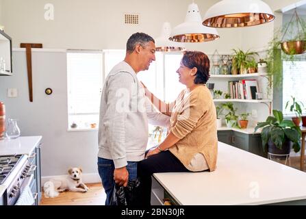 Felice affettuosa coppia matura che parla in cucina Foto Stock