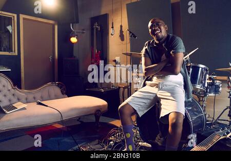 Ritratto felice musicista maschile seduto alla batteria in studio di registrazione Foto Stock