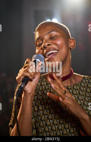 Giovane musicista femminile che canta nel microfono Foto Stock