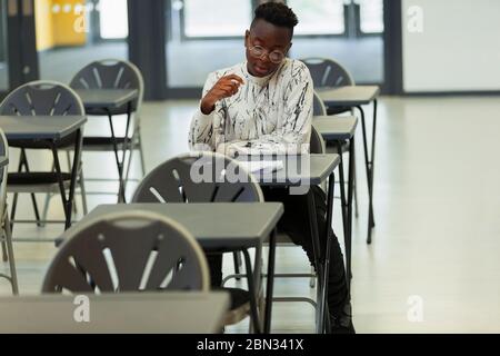 Studente di ragazzo di scuola superiore che si sta studiando alla scrivania in classe Foto Stock