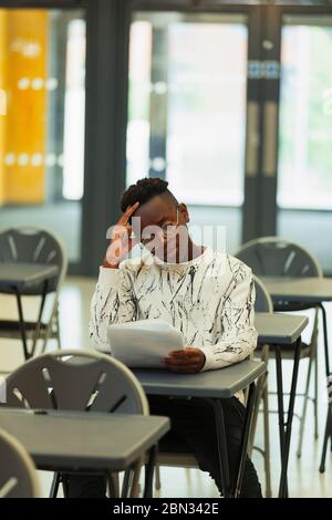 Studente di scuola superiore che si occupa di esami alla scrivania in classe Foto Stock