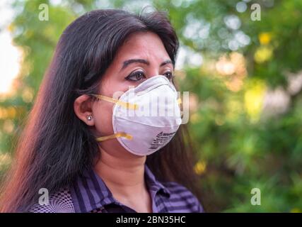 Una signora indiana che usa maschera N95 per proteggersi al momento della malattia pandemica Covid19/ Corona Virus. Foto Stock