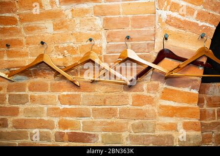 Arredamento della sala pub, appendiabiti in legno appesi su un muro ad arco in mattoni rossi. Foto Stock