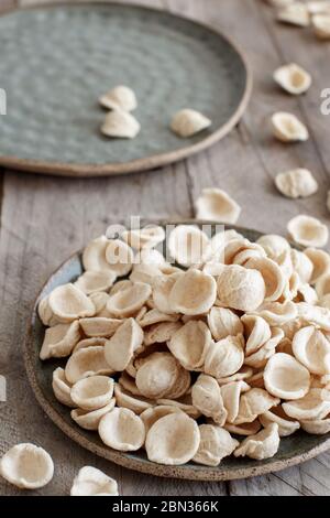 Orecchiette di pasta pugliese cruda e fresca a base di farina integrale su un tavolo di legno da primo piano Foto Stock