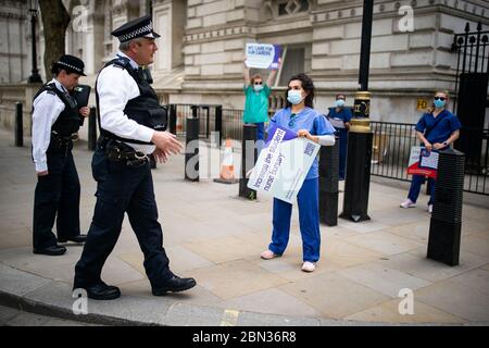 La polizia parla con gli infermieri degli ospedali del centro di Londra protestando per la giornata internazionale degli infermieri circa il cronico sottofinanziamento del NHS e altre questioni che circondano il servizio sanitario al di fuori delle porte di Downing Street, protesta di Londra , dopo l'annuncio dei piani per portare il paese fuori dalla serratura. Foto Stock