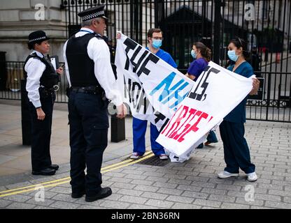 La polizia parla con gli infermieri degli ospedali del centro di Londra protestando per la giornata internazionale degli infermieri circa il cronico sottofinanziamento del NHS e altre questioni che circondano il servizio sanitario al di fuori delle porte di Downing Street, protesta di Londra , dopo l'annuncio dei piani per portare il paese fuori dalla serratura. Foto Stock