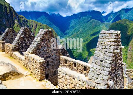 Rovine di pietra dell'antica città Inca di Machu Picchu con montagne e nuvole drammatiche sullo sfondo, Valle Sacra, Perù Foto Stock