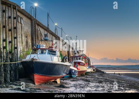 Al crepuscolo dell'alba, una fila di barche da pesca costeggiano il molo ad Appledore nel Devon del Nord, in attesa di un'alta marea prima che possano iniziare a lavorare. Foto Stock