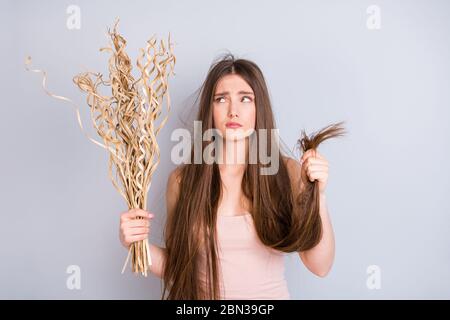 Foto di attraente displayed signora tenere asciutto basso idratazione equilibrio capelli finisce lungo danneggiato sottile debole come paglia mazzo ricci indossare beige singlet Foto Stock