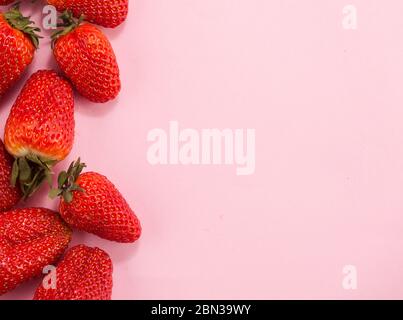 Fragole fresche naturali in ciotola bianca su morbido sfondo rosa con spazio per la copia del testo Foto Stock