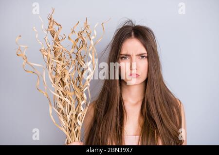 Foto di attraente sollecitato donna preoccupato secco bassa idratazione equilibrio capelli lungo danneggiato sottile debole come paglia arricciate indossare beige singlet isolato grigio Foto Stock