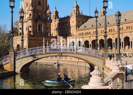 Siviglia, Spagna: 23 dicembre 2019: I turisti vanno in barca a remi intorno all'acqua del fiume Guadalquivir in Plaza de Espana. Giorno di sole, Siviglia, Spagna Foto Stock