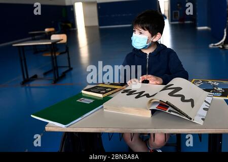 BORGOSESIA, ITALIA - 12 maggio 2020: Un bambino della scuola elementare che indossa una maschera siede in un'aula all'interno di una palestra, nell'ambito di un test pilota per vedere come le scuole possono riaprirsi dopo il blocco del coronavirus COVID-19 nella regione piemontese, proposto dal sindaco di destra di Borgosesia (Vercelli) Paolo Tiramani. (Foto di Nicolò campo/Sipa USA) Foto Stock