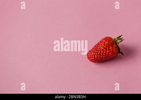 Fragole fresche naturali in ciotola bianca su morbido sfondo rosa con spazio per la copia del testo Foto Stock