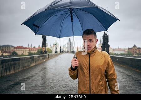 Uomo solitario con ombrello in forte pioggia sul ponte Carlo vuoto. Praga Repubblica Ceca Foto Stock