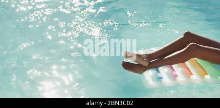 Giovane donna spensierata su una zattera in piscina soleggiata e tranquilla Foto Stock