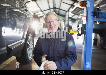 Ritratto sicuro uomo meccanico mani di pulizia in officina di riparazione auto Foto Stock