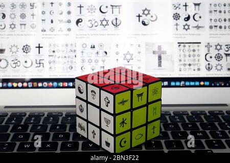 Laptop e cubo di Rubik con simboli religiosi. Concetto di dialogo interreligioso e interreligioso. Foto Stock