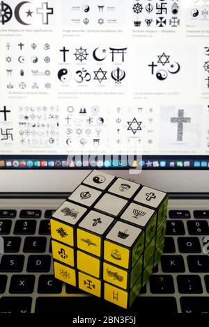 Laptop e cubo di Rubik con simboli religiosi. Concetto di dialogo interreligioso e interreligioso. Foto Stock