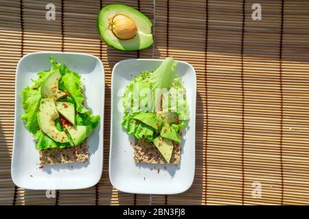 pane croccante con insalata e avocado su un piatto bianco vista dall'alto. Dieta sana e sana colazione spazio copia Foto Stock