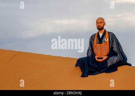 Zen sesshin (ritiro) nel deserto del Sahara, Marocco. Maestro Zen praticando zazen (meditazione). Foto Stock