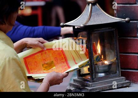 Tempio taoista di Guan di chinese. Donna che brucia carta di joss offerte in forno. Kuala Lumpur. Malesia. Foto Stock